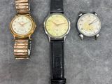 three different watches sitting on a table next to each other
