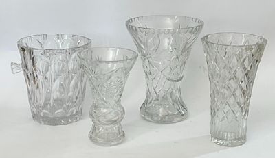 quatre vases en verre et un pichet posés sur une surface blanche