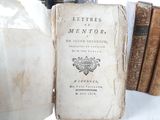 an old book sitting on top of a table next to a bunch of books