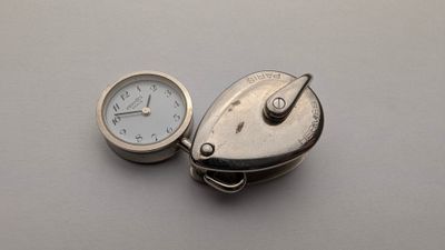 une montre de poche en argent et une horloge en argent posée sur une table