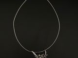 un collier en argent sur fond noir, orné d'un oiseau