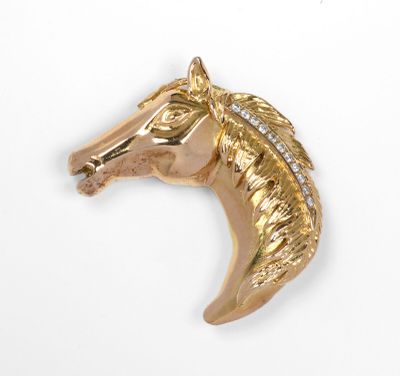 un gros plan d'une broche en forme de tête de cheval en or sertie de diamants