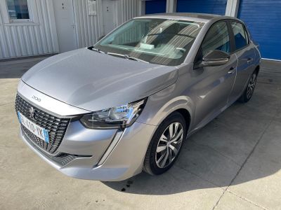 La voiture argentée est garée devant un garage bleu.