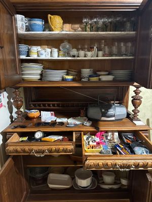 a wooden cabinet with many dishes and cups in it
