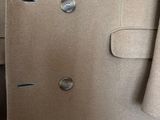 the coat is tan and has buttons on it