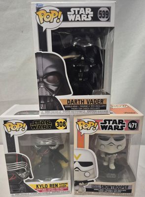 Trois figurines Pop Vinyl de Star Wars sont posées sur une surface blanche