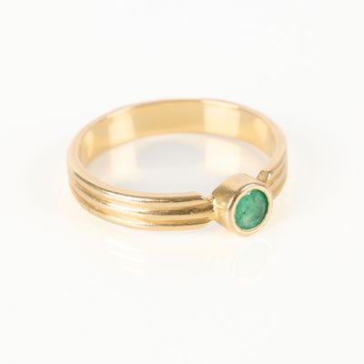 gros plan d'une bague en or avec une pierre verte