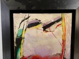 abstract painting in a black frame hanging on a wall