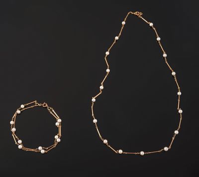 a gold necklace, bracelet and bracelet with pearls on a black background