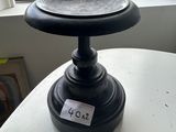 a black candle holder on a white table by a window