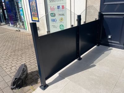 une clôture noire sur le trottoir, à côté d'un immeuble
