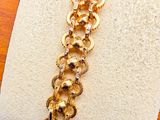 bracelet with a gold chain on a wooden stand on a black background