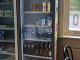 a glass door refrigerator in the corner of a room with a table and chairs
