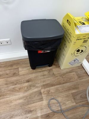 une poubelle noire posée à côté d'une autre poubelle noire