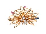 un gros plan sur une broche en or sertie de pierres multicolores