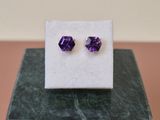 une paire de boucles d'oreilles en améthore posée sur un bloc de marbre