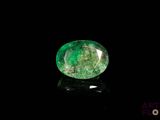 a close up of a green emerald stone on a black surface
