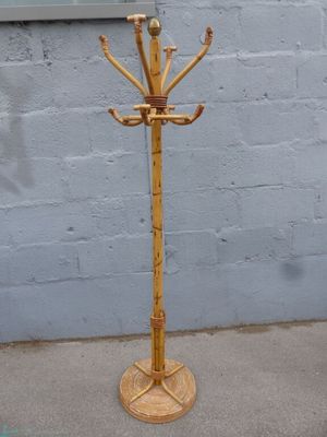 a wooden coat rack on a sidewalk next to a brick wall