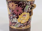 a vase with a handle that has flowers on it