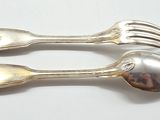 two silver spoons and a fork on a white surface