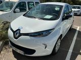 une voiture blanche garée sur un parking, avec d'autres voitures en arrière-plan