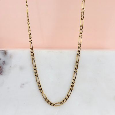une photo d'un collier à chaîne en or posé sur une surface en marbre