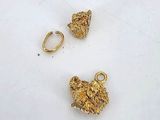 two gold nuggies on a white surface next to a pair of earrings