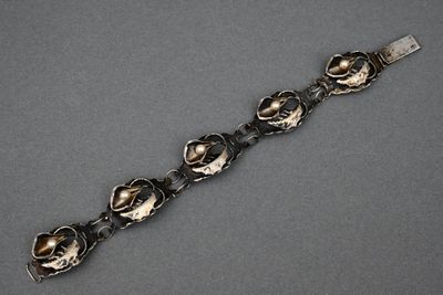 silver bracelet with flowers and leaves on it on a gray surface