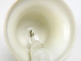 a white cup that has a broken handle in it