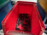 a red container filled with screws and nuts on the floor