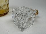 a small crystal cube sitting next to a glass jar