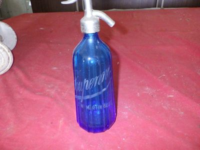a blue glass bottle with a silver lid on a table