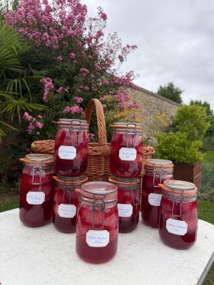 Plusieurs pots de confiture sont posés sur une table devant un panier de fleurs