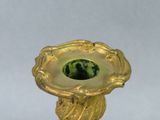 a gold candle holder with a green stone in it