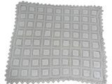 a white crocheted blanket on a white surface