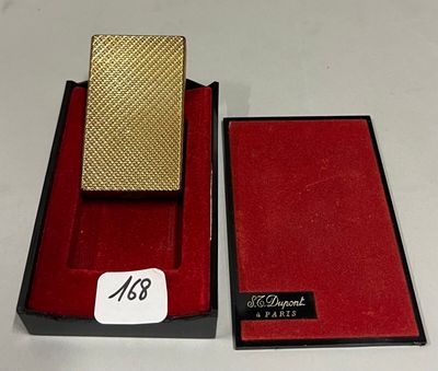 un briquet doré dans une boîte rouge posée sur une table blanche