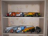 de nombreux camions miniatures et camions posés sur une étagère dans une pièce