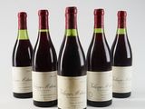 four bottles of wine are lined up on a white surface