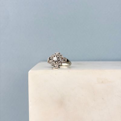 une image représentant une bague en diamant posée sur un bloc de marbre blanc