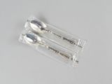 three silver spoons in a clear bag on a table