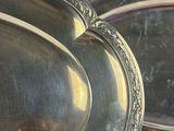 two oval silver trays sitting on a table