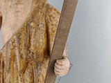 wooden statue of a man holding a cross and a wooden stick