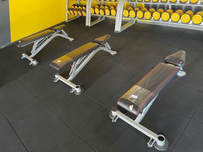 une salle de sport avec une rangée d'haltères et une rangée de bancs