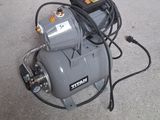 a small air compressor sitting on the ground next to a hose