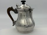 une cafetière ancienne en argent avec une poignée en bois sur un fond blanc