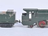 un petit train vert posé à côté d'un autre petit train sur une surface blanche