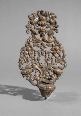an ornate metal object with a bird and flowers on it