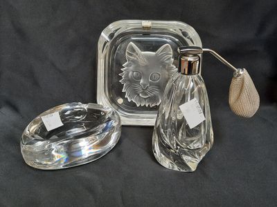 two clear glass bottles and a silver plate with a cat on it