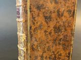 an old book sitting on top of a table next to a gray wall
