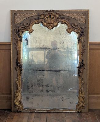 un grand miroir posé sur un parquet dans une pièce